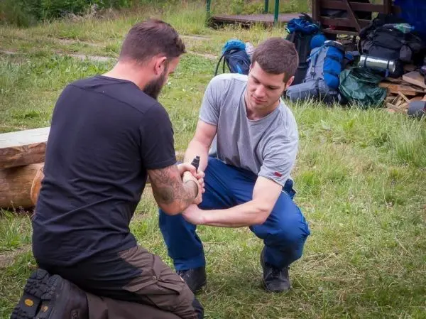 Zwei Personen üben eine Technik zur Handhabung eines Messers im Freien