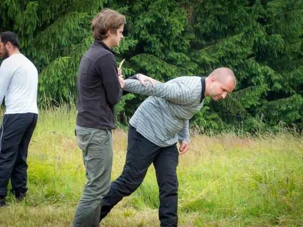 Zwei Personen üben eine Technik zur Kontrolle des Gegners auf einer Wiese