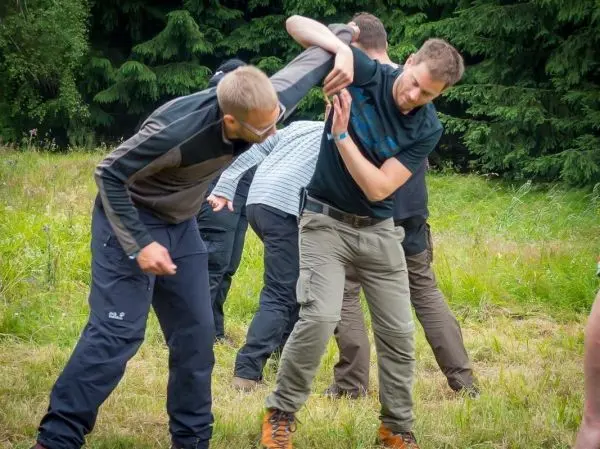 Zwei Personen üben einen Griff in einer Trainingssituation auf einer Wiese