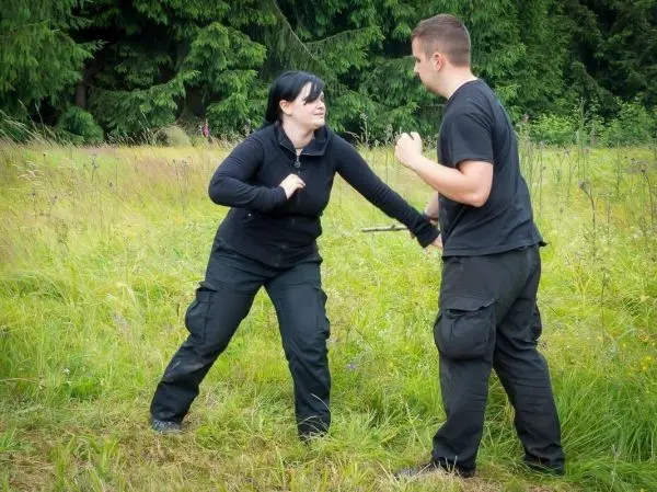 Zwei Personen üben Selbstverteidigungstechniken in einem grasbewachsenen Bereich