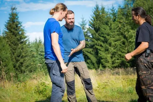 Drei Personen stehen auf einer Wiese und sprechen miteinander