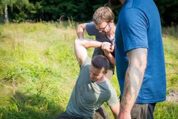 Drei Personen üben eine Technik zur Unterstützung im Stehen aus