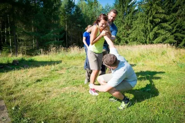 Eine Person wird von einer anderen unterstützt, während eine dritte Person hilft