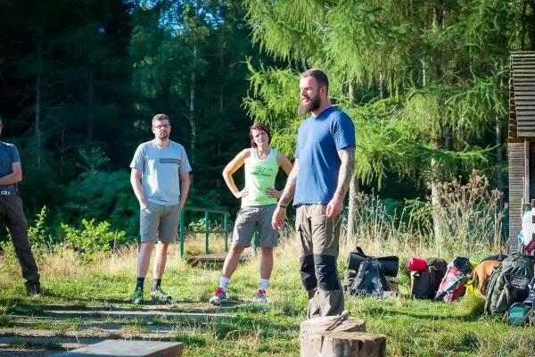 Gruppe steht auf einer Wiese, Rucksäcke und Ausrüstung im Hintergrund