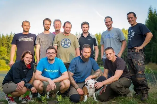 Gruppe von Männern und einer Frau posiert mit Hund im Freien