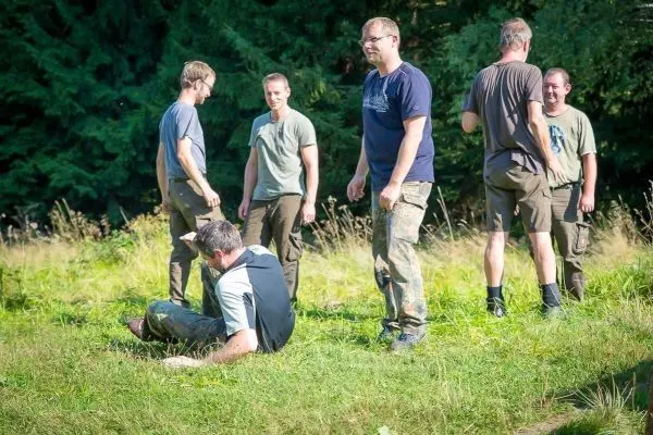 Gruppe von Personen steht und sitzt auf einer Wiese in der Natur