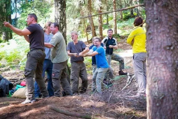 Gruppe zieht an einem Seil während einer Seilquerung im Wald