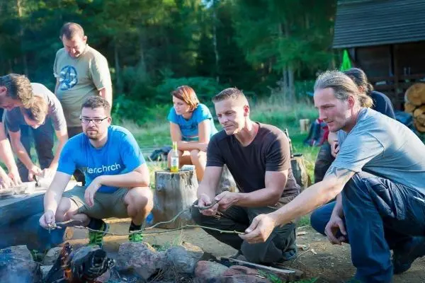 Gruppierung um ein Feuer, einige halten Stöcke über die Flamme