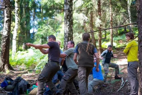 Gruppierung zieht an einem Seil in einem Waldgebiet zwischen Bäumen