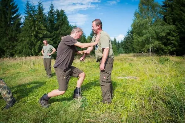 Kampftraining mit zwei Personen in einer Wiese, eine Person greift die andere an