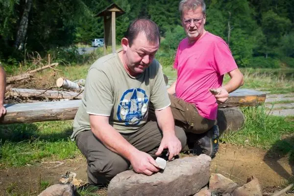 Mann bearbeitet Stein mit einem Werkzeug auf einem Bodenfeuerplatz