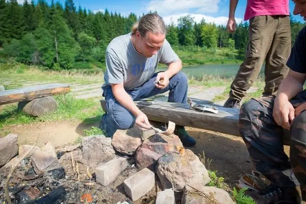 Mann bereitet Essen über einem kleinen Feuer mit Steinen und Holz vor