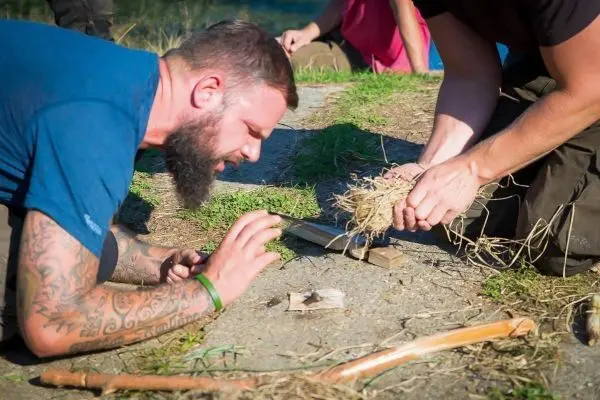 Mann bereitet Zunder für Feuerbohrer-Technik vor