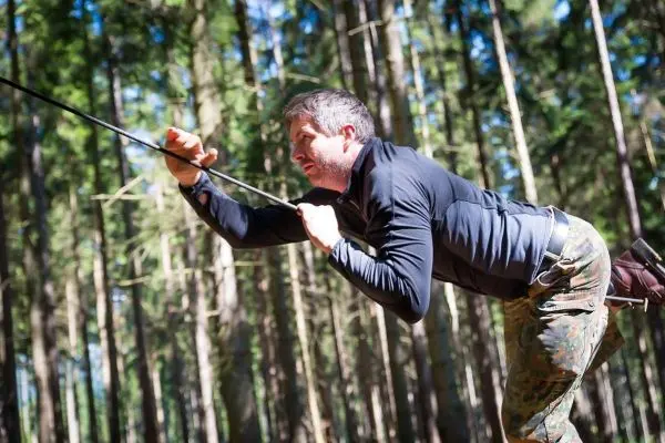 Mann führt eine Seilquerung in einem Waldgebiet durch