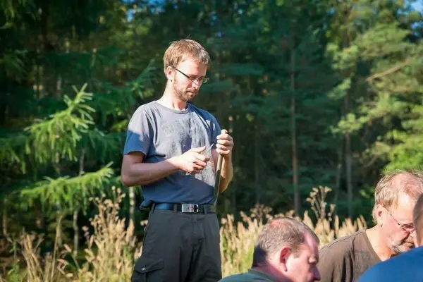 Mann hält ein Messer in der Hand und schaut konzentriert darauf