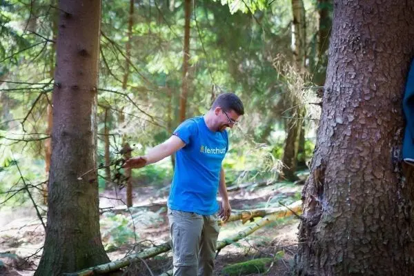 Mann hält einen Stock in einem Waldgebiet zwischen Bäumen
