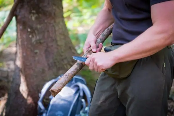 Messer schält einen Stock im Wald