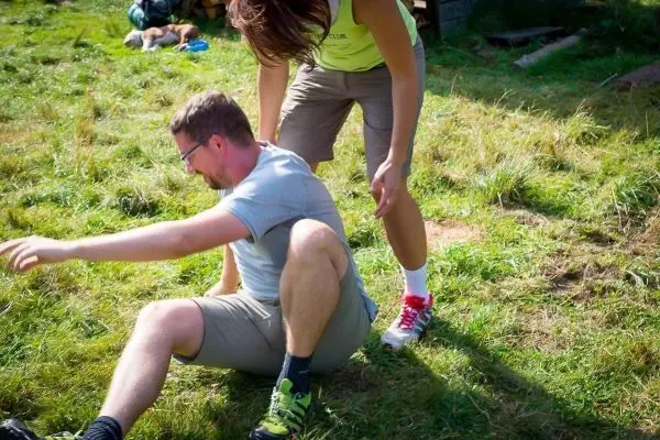 Person hilft sitzender Person auf dem Gras