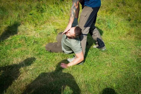 Person liegt auf dem Boden, während eine andere Person sie festhält
