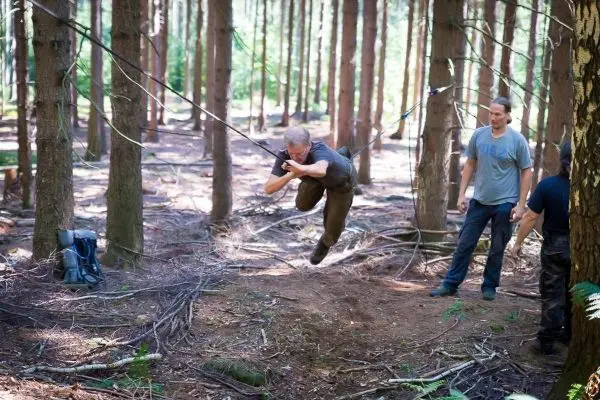 Person schwingt an Seil zwischen Bäumen im Wald