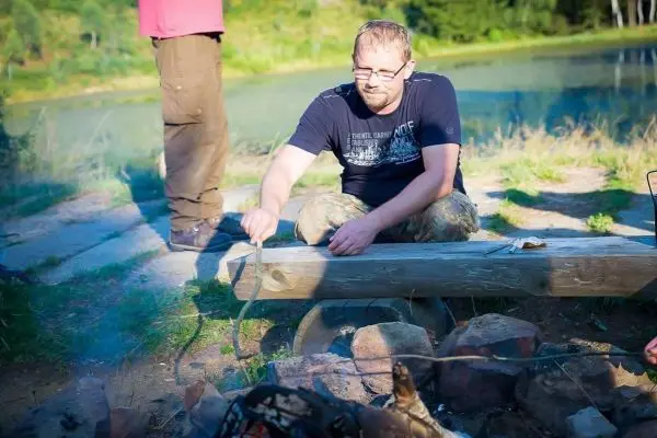 Person sitzt am Lagerfeuer und hält einen Stock in der Hand