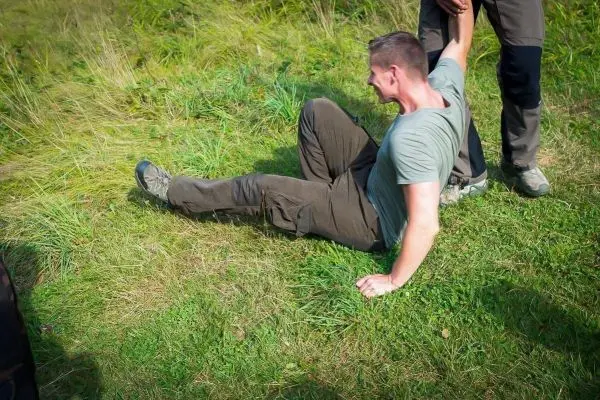 Person sitzt auf dem Boden und wird von einer anderen Person hochgezogen