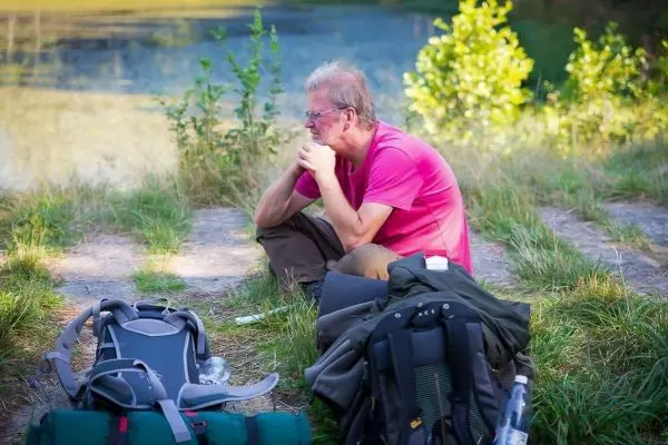 Person sitzt nachdenklich auf dem Boden neben Rucksäcken