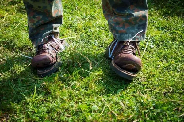 Stiefel stehen auf grünem Gras, Schnürsenkel sind offen