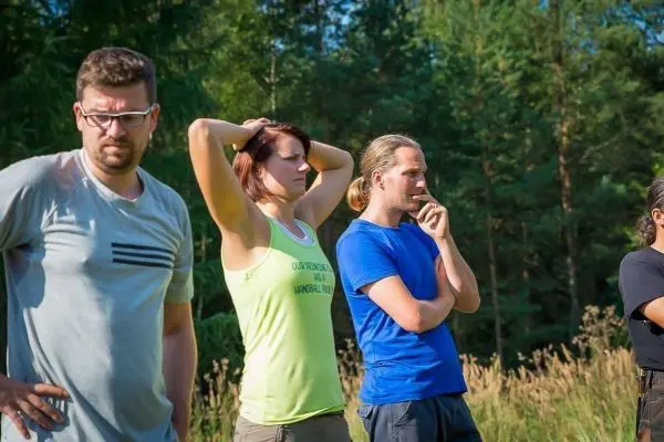 Vier Personen stehen im Freien und beobachten aufmerksam