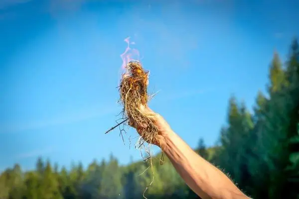 Zunder glimmt in der Hand und erzeugt kleine Flammen