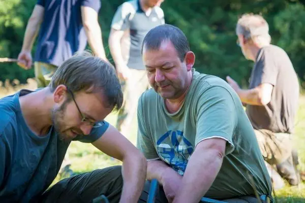 Zwei Personen arbeiten am Boden, während andere im Hintergrund beschäftigt sind