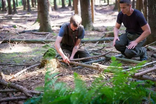 Zwei Personen arbeiten im Wald an einer Holzstruktur
