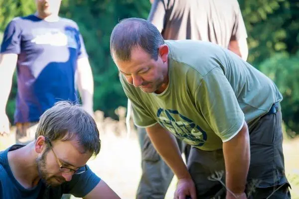 Zwei Personen beugen sich über eine Bodenfläche und betrachten etwas