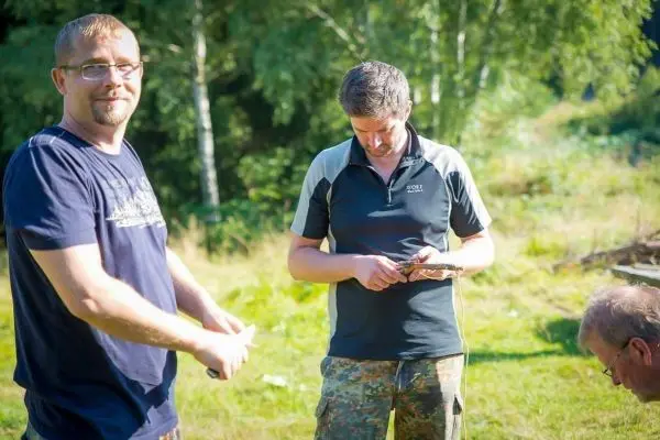 Zwei Personen halten Werkzeuge in der Hand, während eine dritte Person am Boden arbeitet