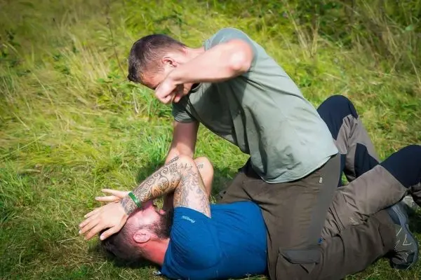 Zwei Personen im Bodenkampf, einer drückt den anderen am Boden