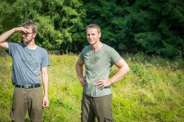 Zwei Personen stehen in einer Wiese und schauen in die Ferne