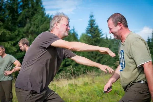 Zwei Personen stehen sich gegenüber und lachen miteinander beim Training