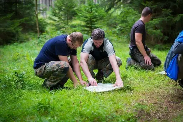Zwei Personen studieren eine Karte auf dem Boden im Wald
