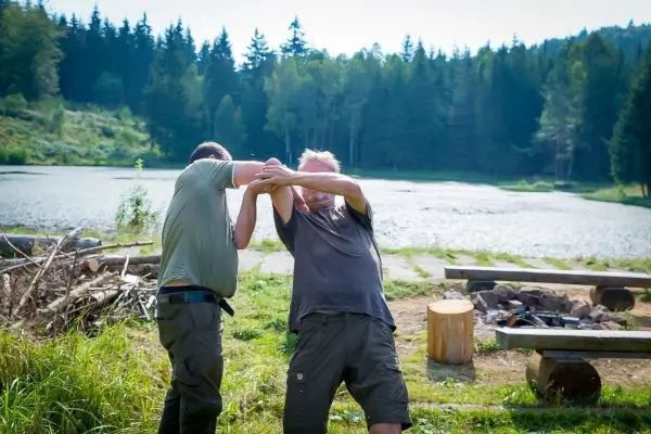Zwei Personen üben eine Selbstverteidigungstechnik am Ufer eines Gewässers
