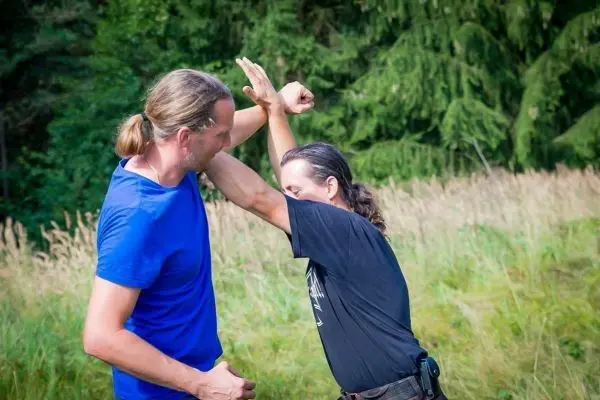 Zwei Personen üben eine Selbstverteidigungstechnik im Freien
