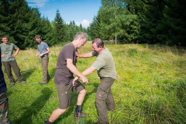 Zwei Personen üben eine Selbstverteidigungstechnik in einer Wiese