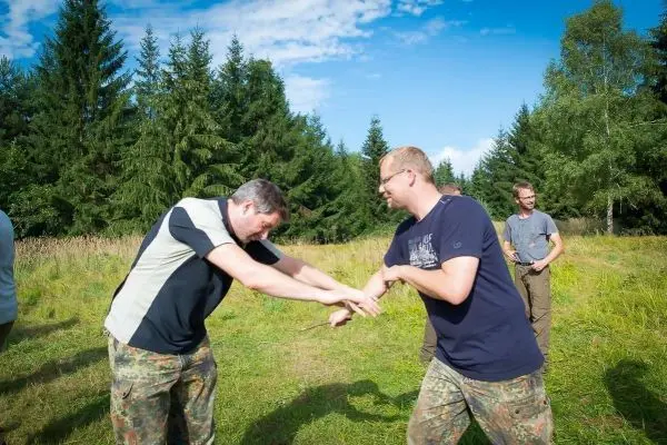 Zwei Personen üben eine Technik im Freien auf einer Wiese