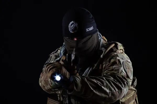 Bewaffnete Person zielt mit einer Pistole und nutzt eine Taschenlampe