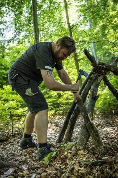 Axt spaltet Holz für eine selbstgebaute Struktur im Wald