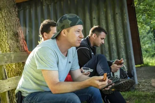 Drei Personen sitzen auf einer Bank und schauen auf ihre Smartphones