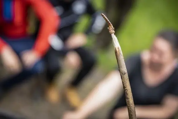 Ein angespitzter Stock mit einem Wurm auf der Spitze liegt im Vordergrund