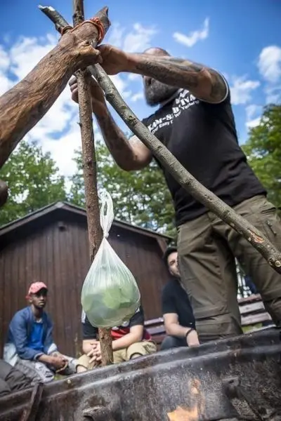 Ein Kessel hängt an einer improvisierten Aufhängung über einem Feuer