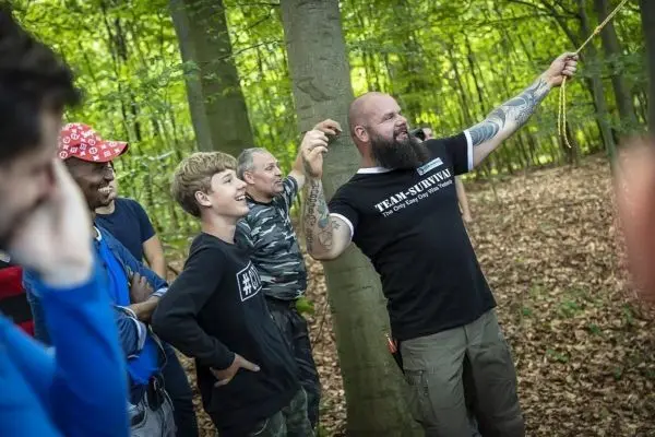 Ein Mann demonstriert eine Knotentechnik mit einem Seil, während Zuschauer aufmerksam zuschauen