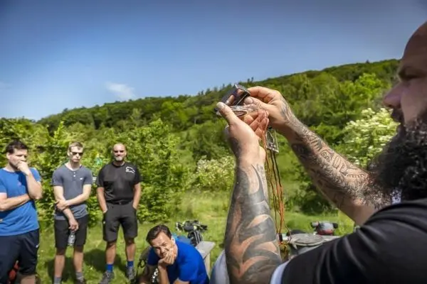 Ein Mann demonstriert eine Kompassnutzung vor einer Gruppe im Freien