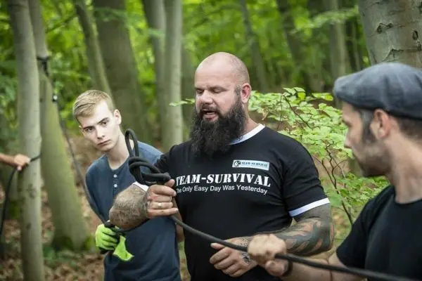 Ein Mann demonstriert Knotentechniken mit einem Seil im Wald